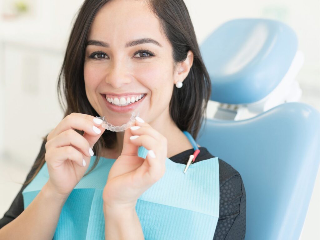 patient holding invisalign clear aligners up to her mouth.