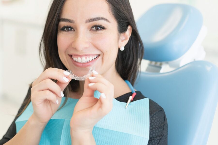 patient holding invisalign clear aligners up to her mouth.